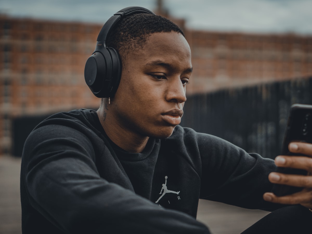 Persona joven con audífonos consultando su teléfono al aire libre