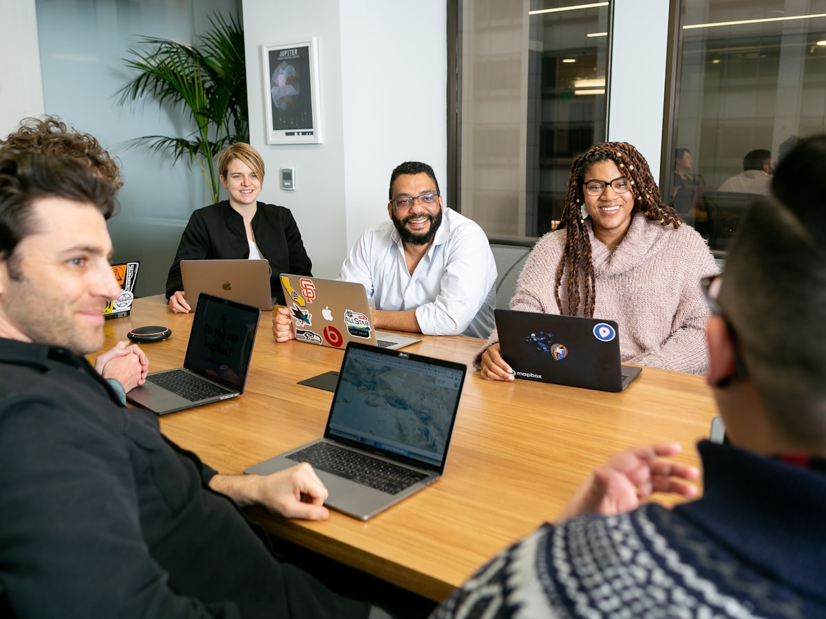 Equipo reunido en torno a una mesa de trabajo con computadores portátiles